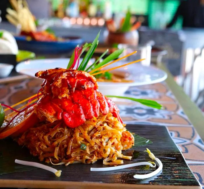 A generous serving of pad thai adorned with large chunks of lobster.