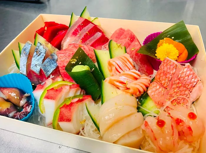 A beautifully arranged wooden box filled with an array of fresh, colorful sashimi