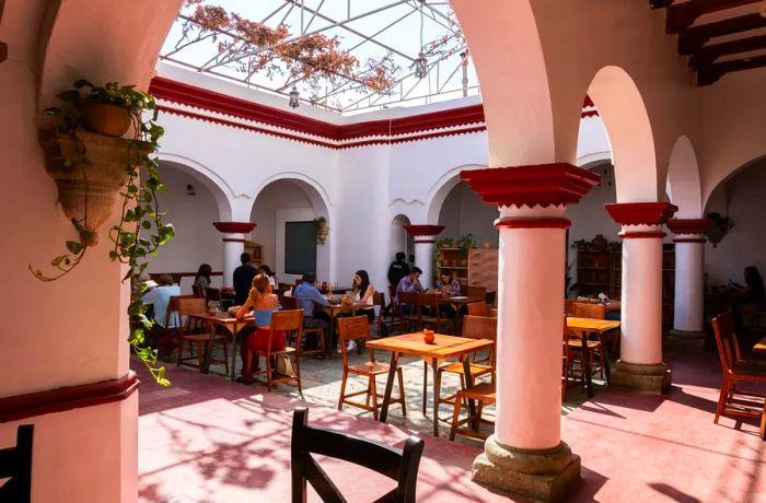 A bright courtyard adorned with columns and arched doorways, bustling with diners at their tables.