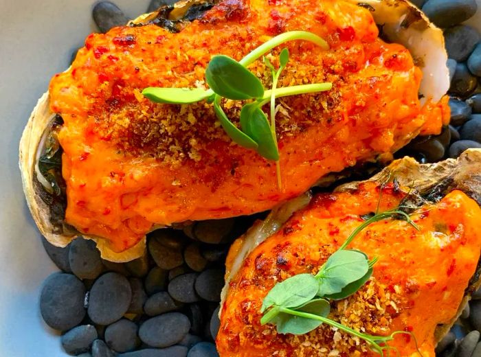 An aerial view of two oysters topped with spicy chili butter and herbs.