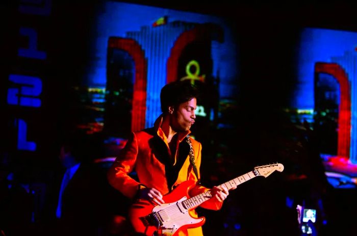 Prince delivering a stunning performance at the Rio Hotel in Las Vegas, adorned in a vibrant orange jacket and playing a matching electric guitar.