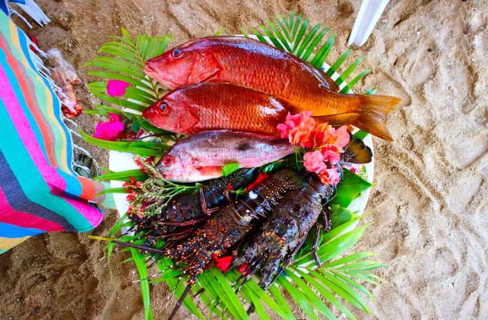 A palm-fringed platter displays an array of fresh raw fish and lobsters.