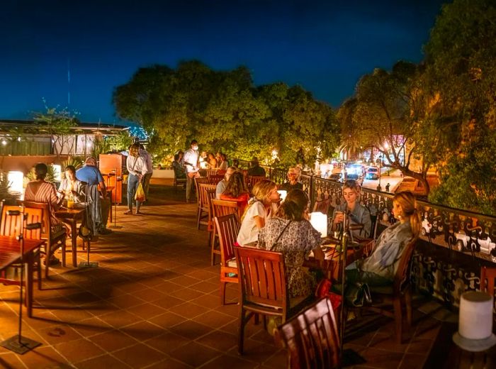 A vibrant nighttime atmosphere on a patio filled with diners at tables.