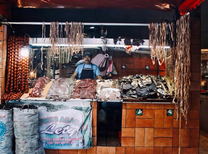 A man is positioned behind a stall filled with dried meat products.