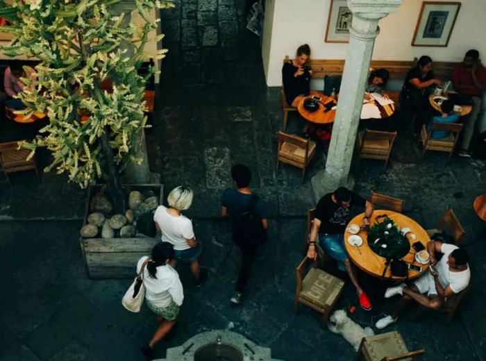 Aerial view of a courtyard bustling with people enjoying coffee at tables.