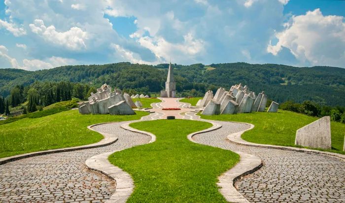 A serene memorial site adorned with large white stones and a church at the end of a pathway