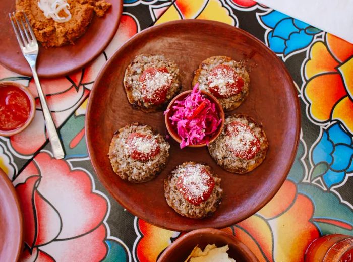 A floral placemat features a brown plate with five round masa discs.