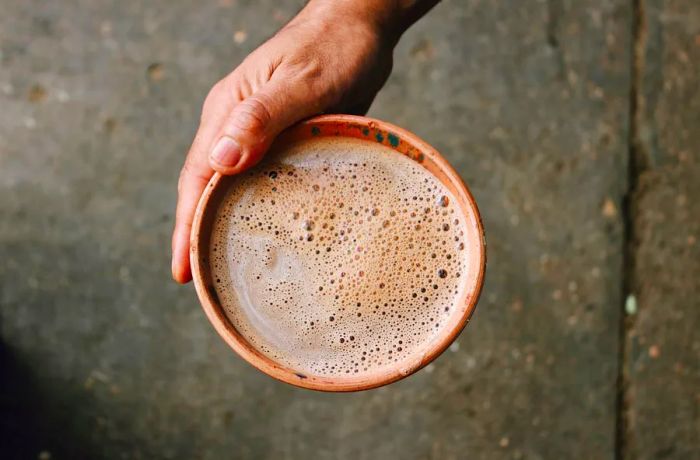 A large, brown bowl filled with frothy chocolate.