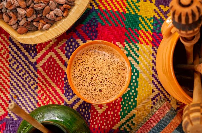 A cup adorned with a layer of brown bubbles rests atop a traditional woven textile.