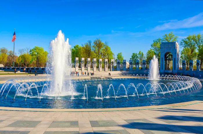 A grand fountain with shooting jets, encircled by memorial cenotaphs.