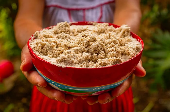 A woman cradles a large bowl filled with sandy-colored, chunky foam.