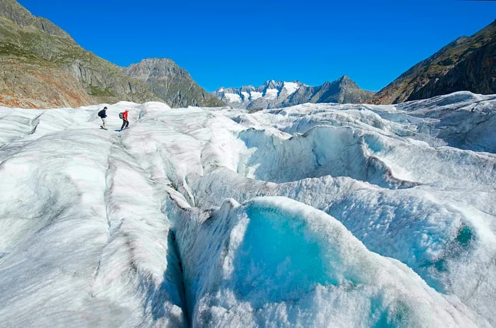 Two hikers traversing the Aletsch Glacier, Valais, Switzerland