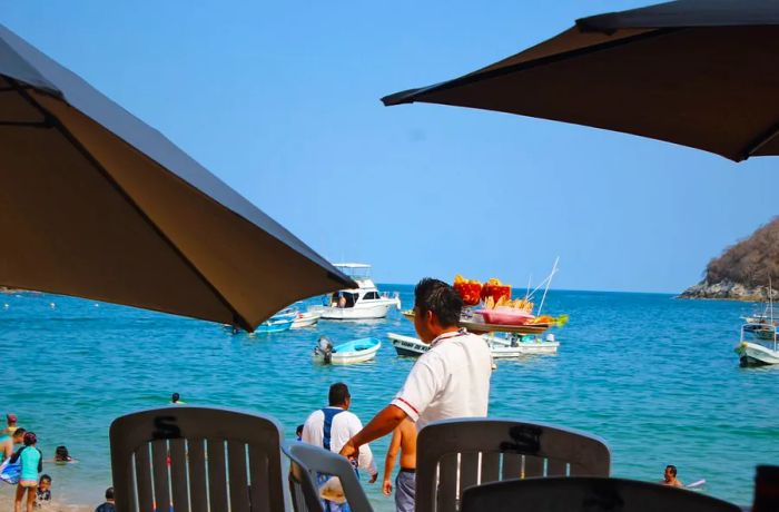 A server transports trays of shrimp cocktail along the beach.