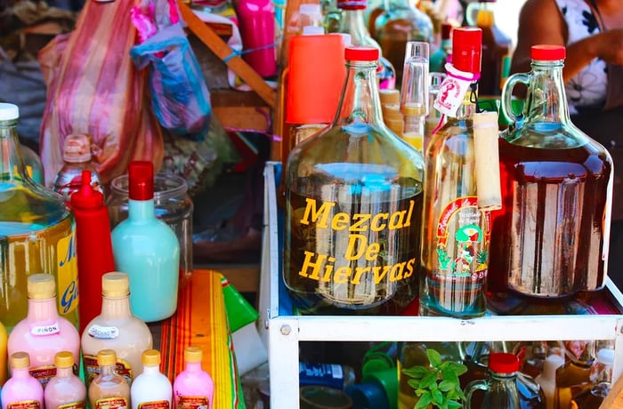 A cart filled with various bottles of mezcal.