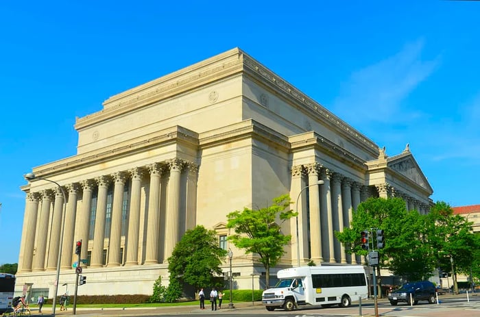 A large building adorned with multiple columns stands majestically outside.