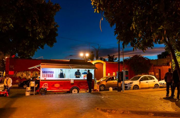 A food truck by the edge of a plaza at night