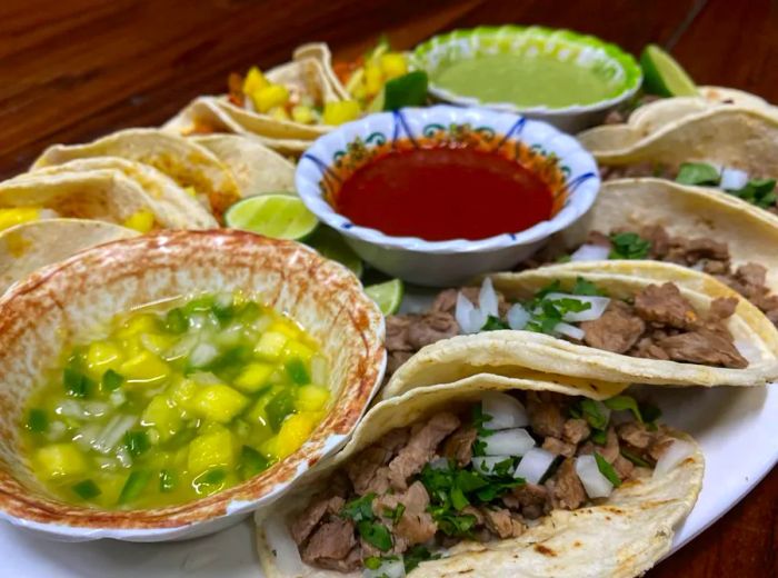 A generous serving of tacos accompanied by bowls of salsa.