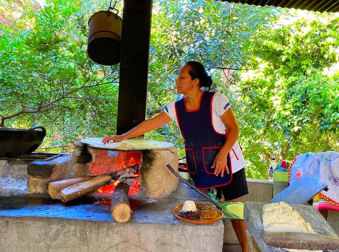 A chef prepares tortillas on a wood-fired comal.