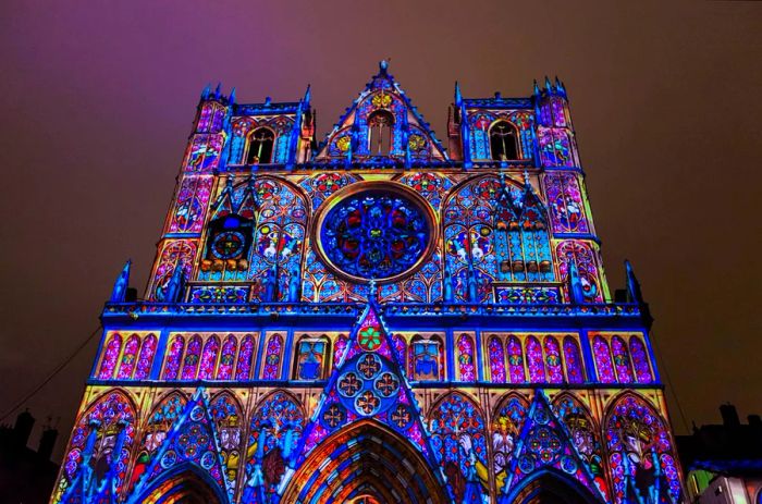 The exterior of Lyon Cathedral, a Roman Catholic cathedral dedicated to Saint John the Baptist, illuminated during the Lumière light festival at night.