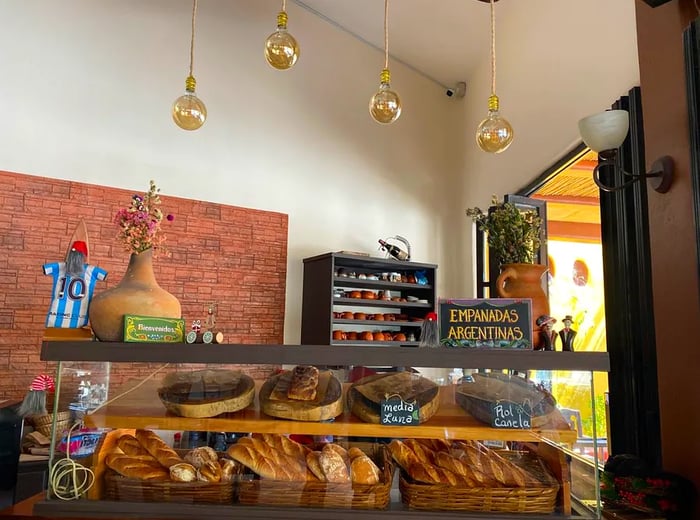 A display case filled with fresh bread in a cozy, open-air bakery.