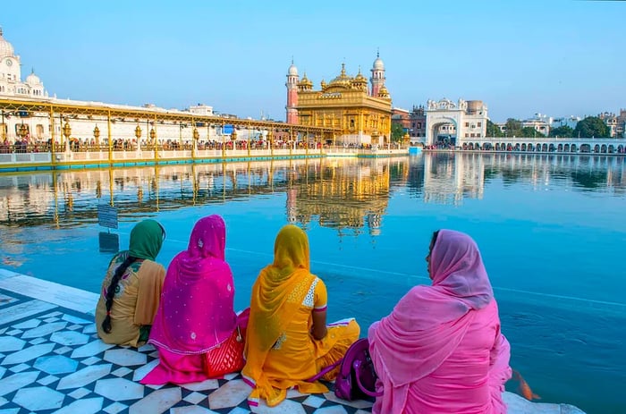 Women dressed in traditional attire by the pool surrounding the Golden Temple in Amritsar, India