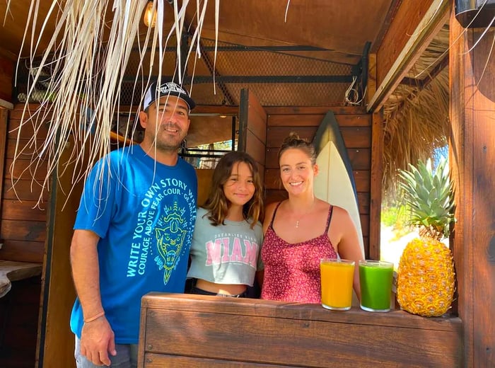 Parents enjoy time with a child at a cozy wooden outdoor bar.