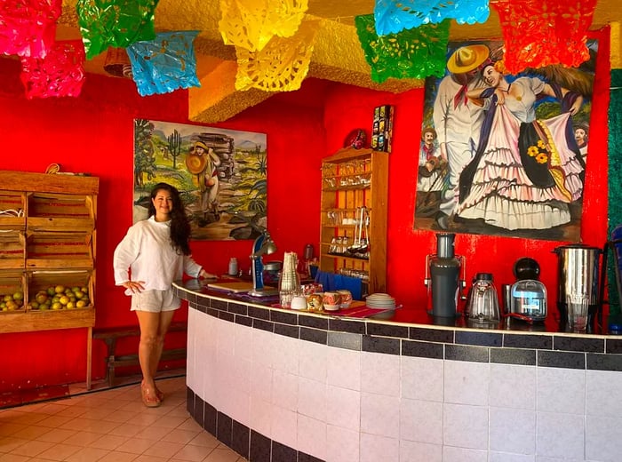 A woman stands at a bar adorned with bright decorations, creating a lively atmosphere.