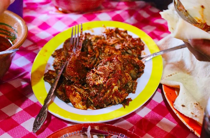 A substantial pile of meat presented on a plate with a yellow rim.