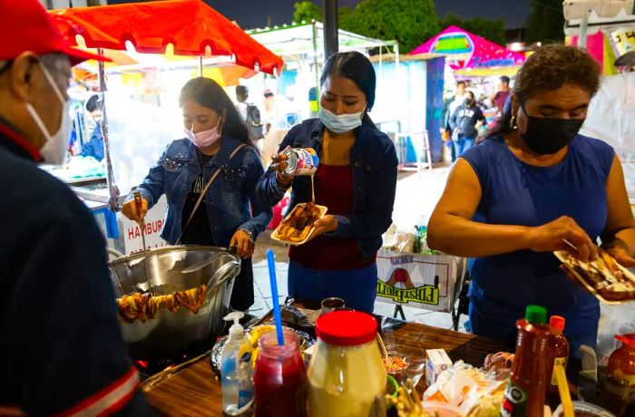 Three women preparing plantains at a street stall.