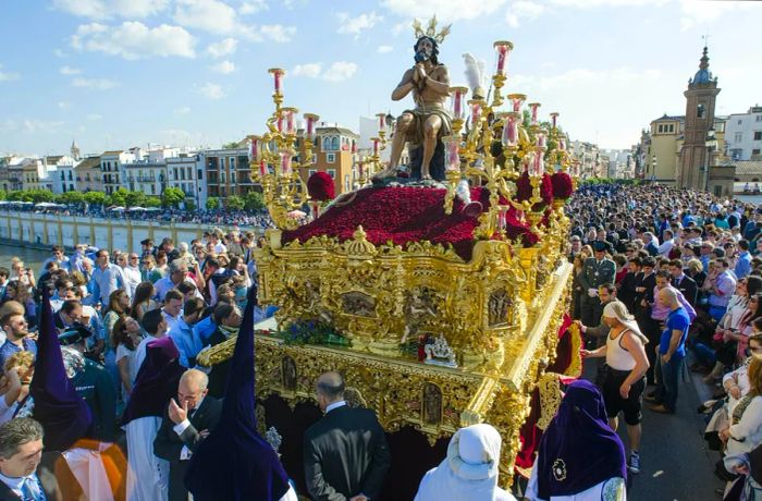 The 'La Estrella' brotherhood parading across the Triana bridge during Semana Santa in Seville.