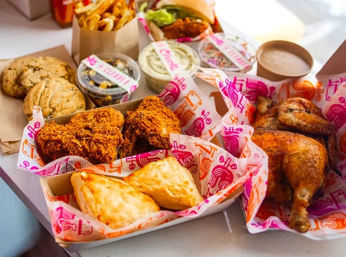 Plates filled with fried chicken and biscuits alongside an array of cookies, French fries, and a fried chicken sandwich.