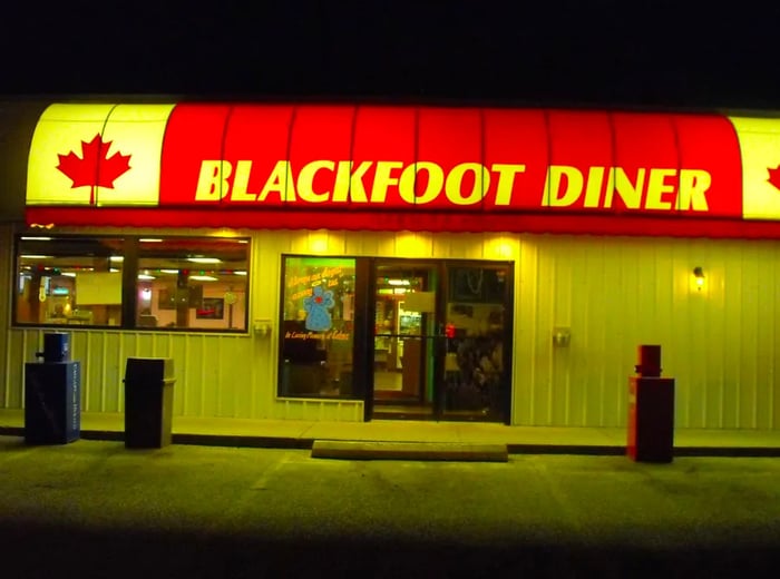 The exterior of a restaurant illuminated at night, showcasing a large sign for Blackfoot Diner adorned with Canadian maple leaves on either side.