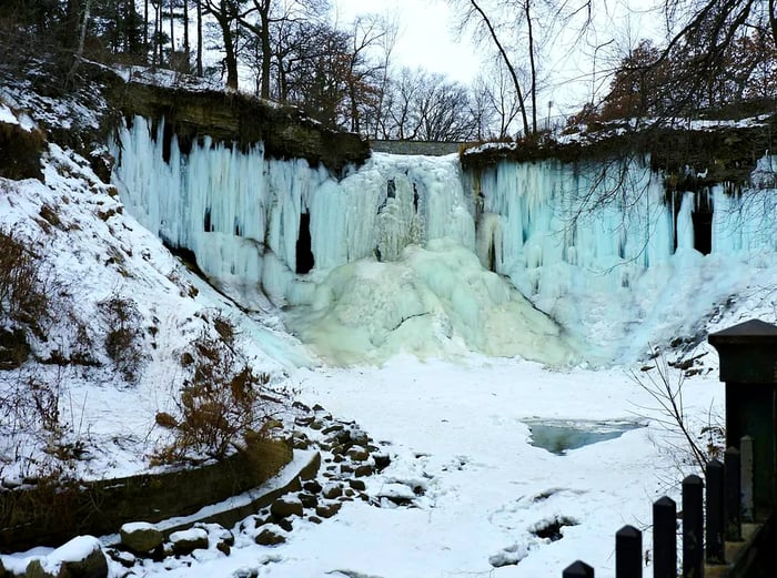 A winter scene of a frozen waterfall embraced by snow