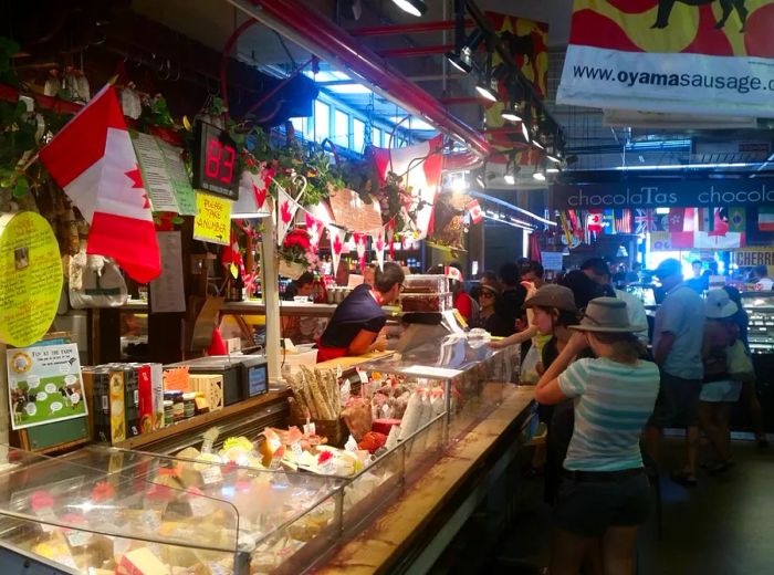 Shoppers explore various food stalls in an indoor market adorned with Canadian flags.