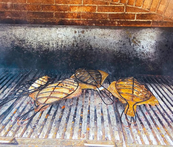 A sizable turbot sizzling on an outdoor grill