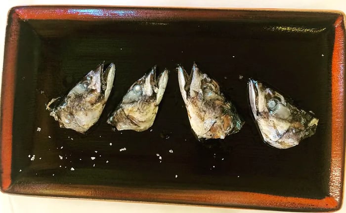 Four grilled fish heads elegantly arranged on a plate