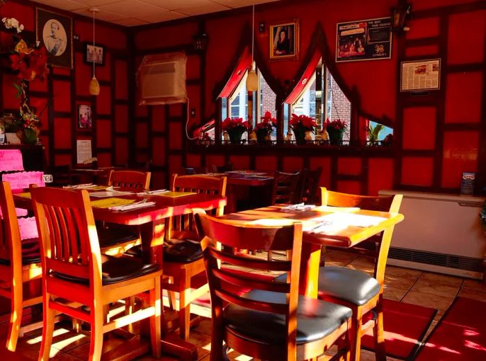 A bright restaurant interior adorned with wood-paneled walls, vintage photographs, and greenery, featuring tables set for dining