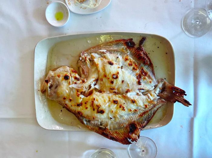 A whole grilled fish presented elegantly on a white tablecloth