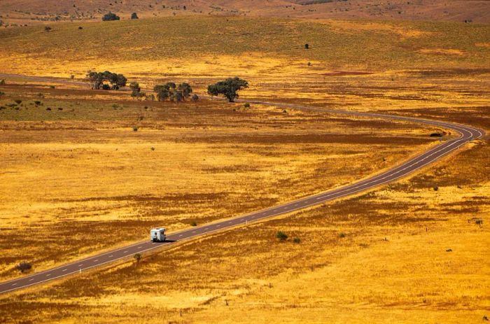 A motor home travels along an expansive road through a wide-open landscape