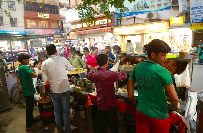 A lineup of vendors at their cooking stations on a busy street.