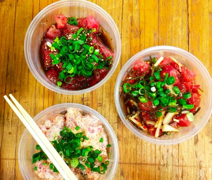 Three poke containers with chopsticks resting across one of them.