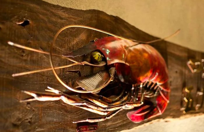 A striking wall sculpture shaped like a large shrimp.