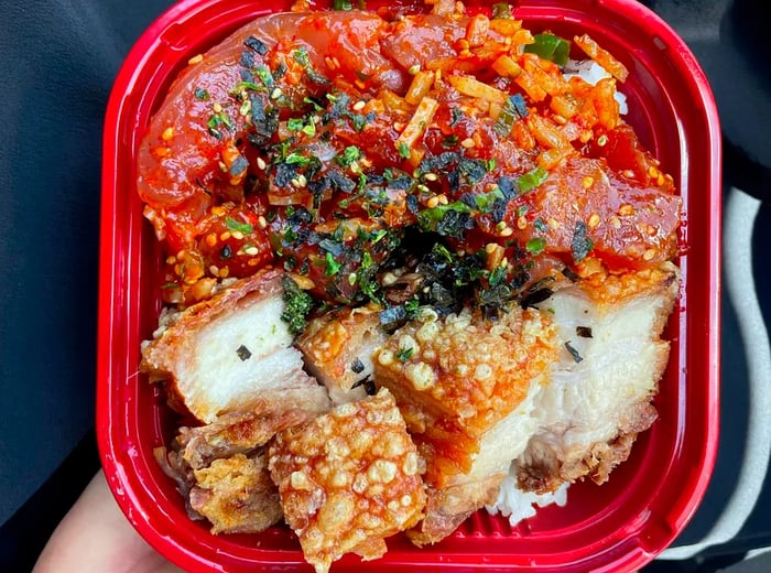 Aerial view of a bowl filled with poke and lechon over rice.