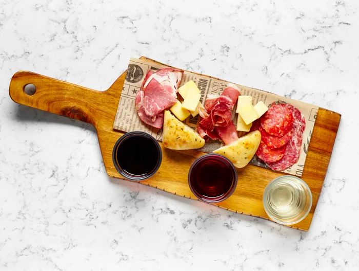 A meat and cheese platter featuring three glasses of wine, captured from above.