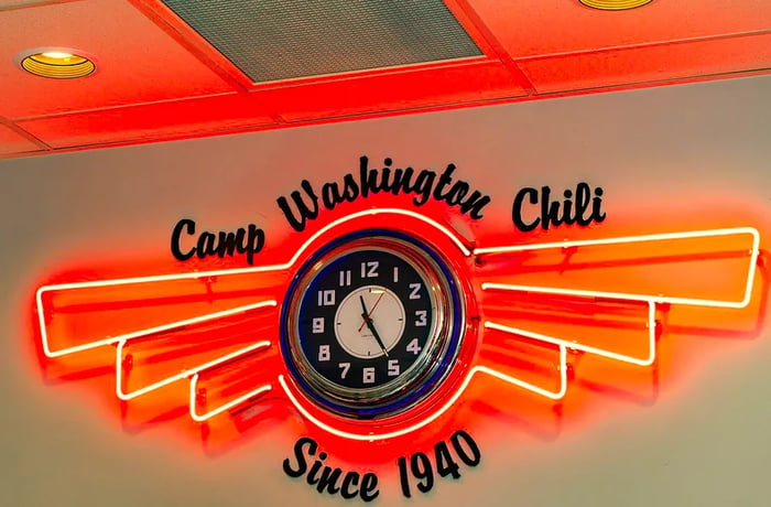 An antique clock encased in vibrant red neon lights. Above it, the wall displays Camp Washington Chili, and below reads Since 1940.