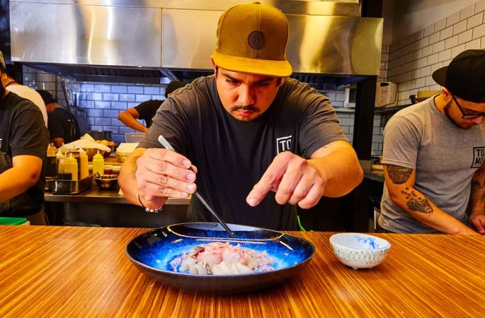 A chef adds the final touches to a plate using tweezers.