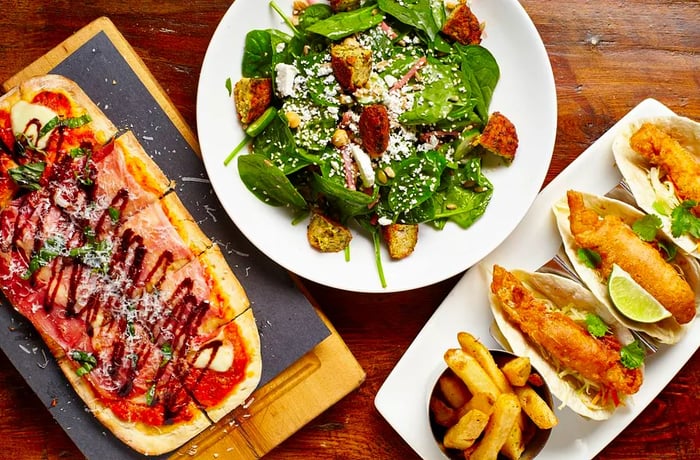 A selection of flatbread pizza, salad, and fried fish tacos