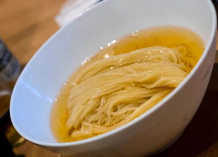 A bowl of noodles immersed in rich broth.