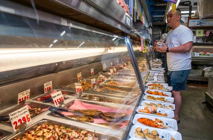 A customer waits at the deli counter for their poke order.