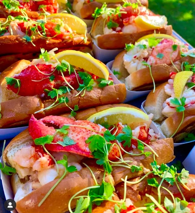 Lobster rolls adorned with sprouts and lemon wedges on an outdoor patio